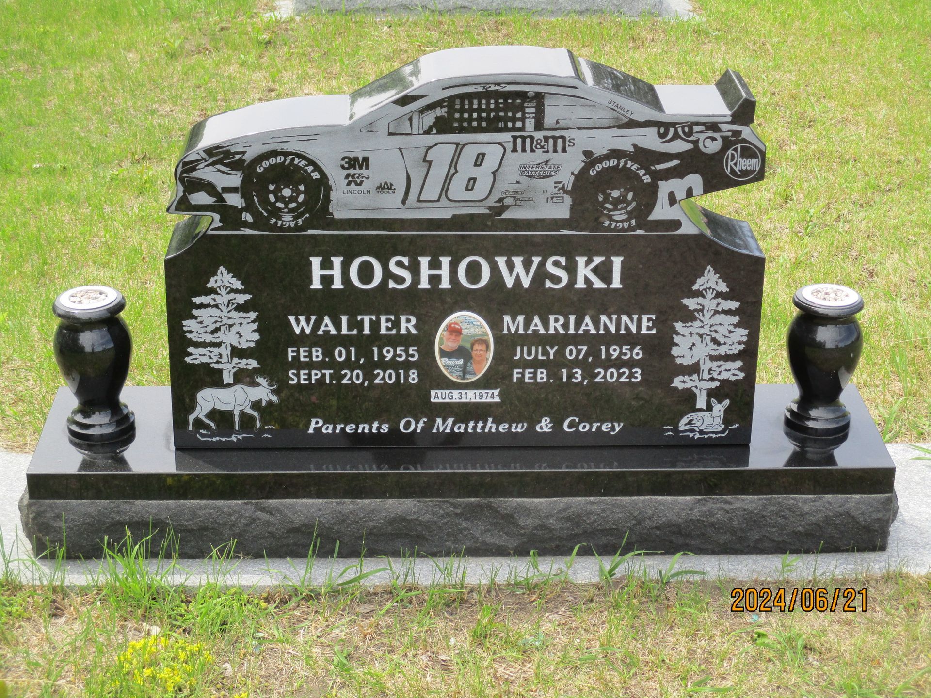 NASCAR-style gravestone with race car engraving, HOSHOWSKI name, and floral tributes on a black memorial base