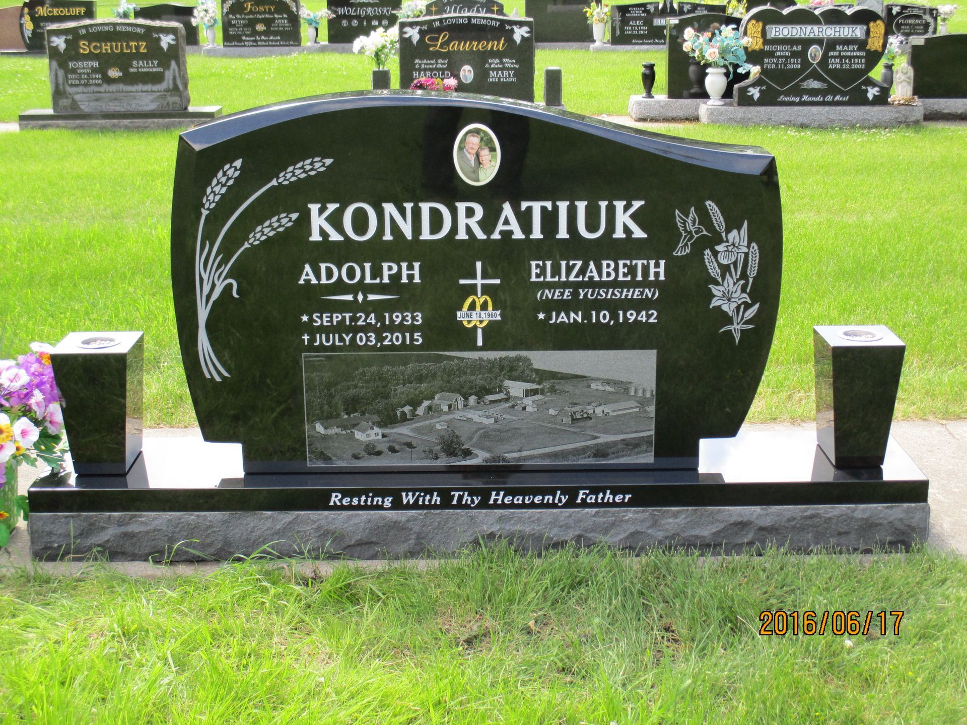Black polished gravestone for Adolph and Elizabeth Kondratiuk in a cemetery lawn