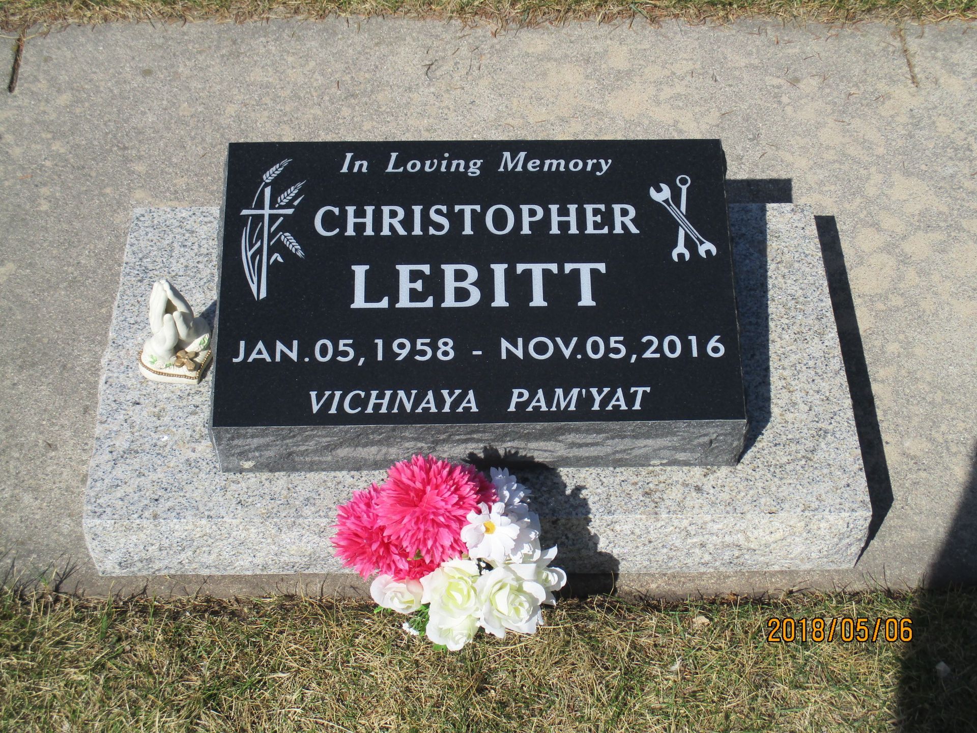 Gravestone for Christopher Lebitt with pink and white flowers at the base.