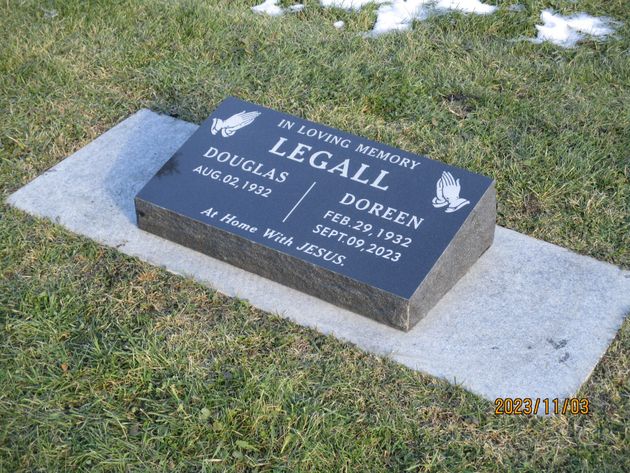 Black granite memorial headstone on a concrete base in a grassy cemetery.