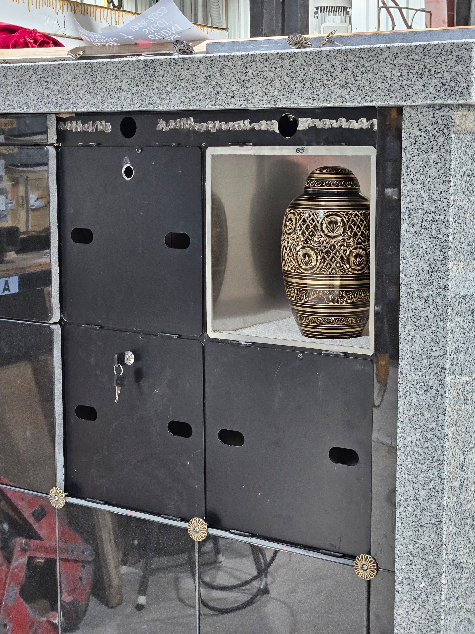 Decorative brass urn in a recessed display niche on a black and gray wall