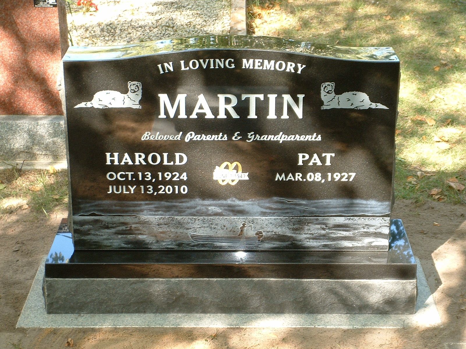 Black marble memorial headstone for Martin with engraved names Harold and Pat, in sunlight outdoors