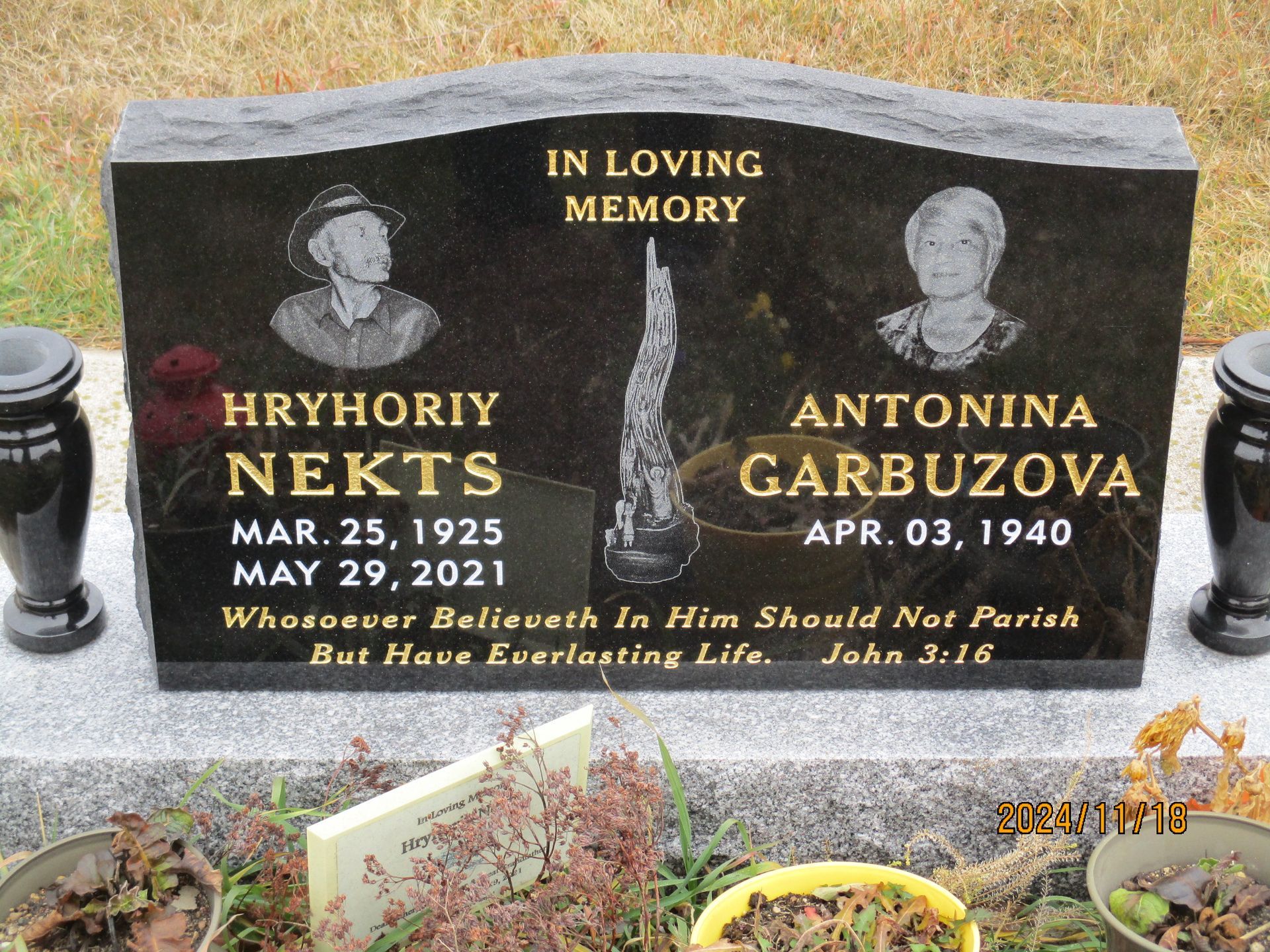 Black memorial gravestone with portraits and gold lettering for Hryhoriy Neks and Antonina Gabrilzov.