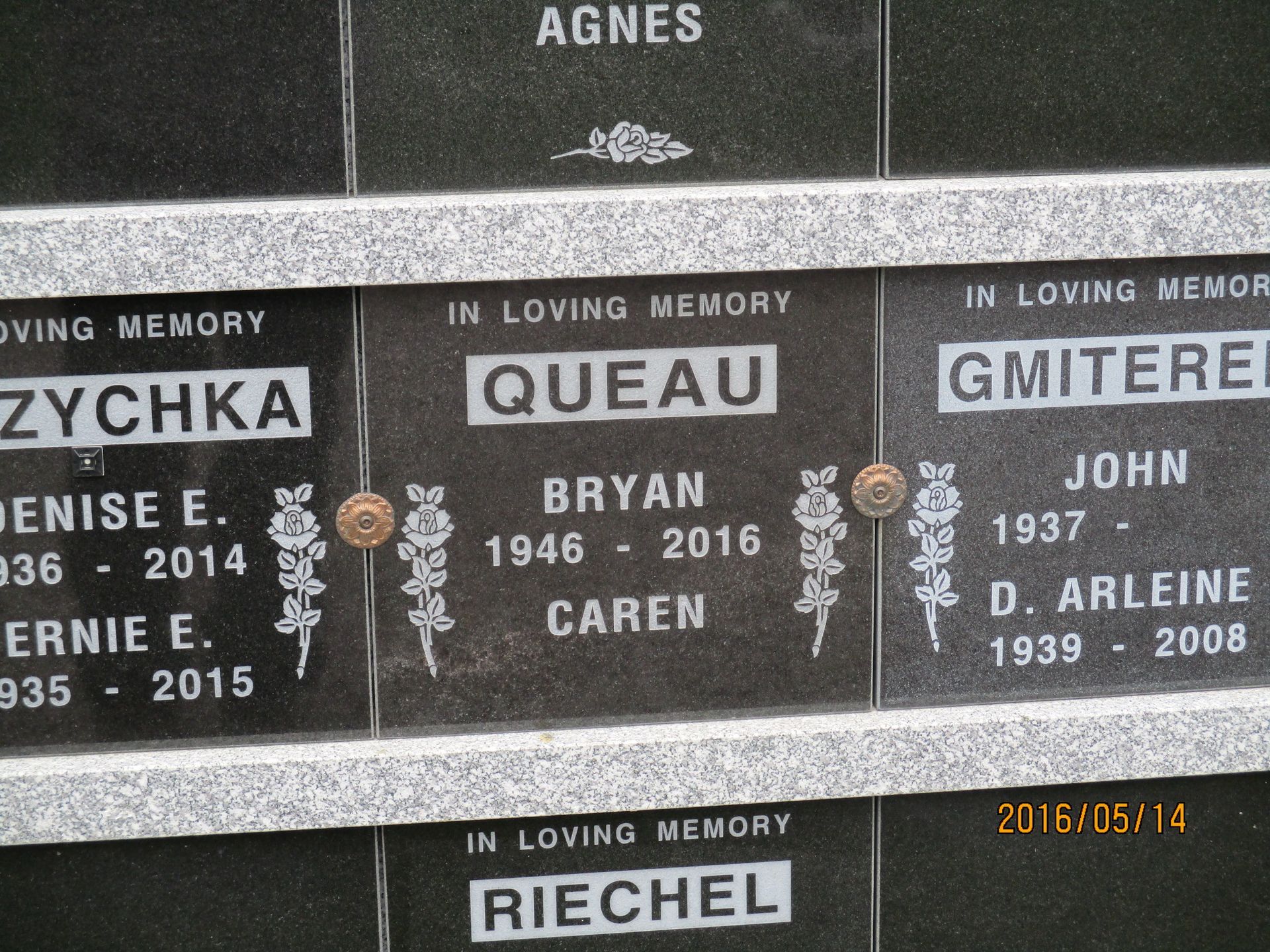 Close-up of engraved memorial plaques with names and years on a dark stone wall.