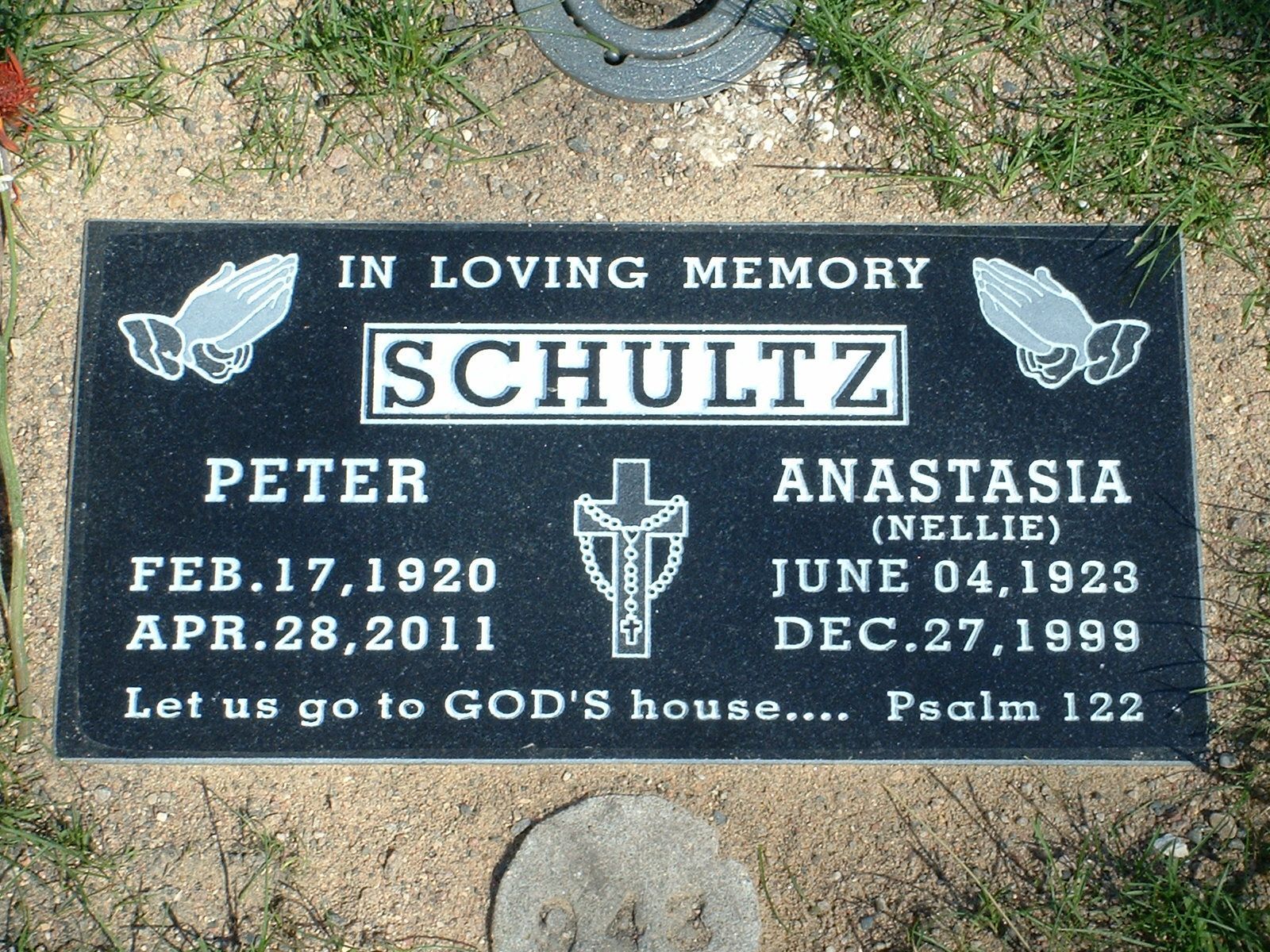 Black memorial gravestone with white lettering for Schultz, Peter, and Anastasia, set in grass.