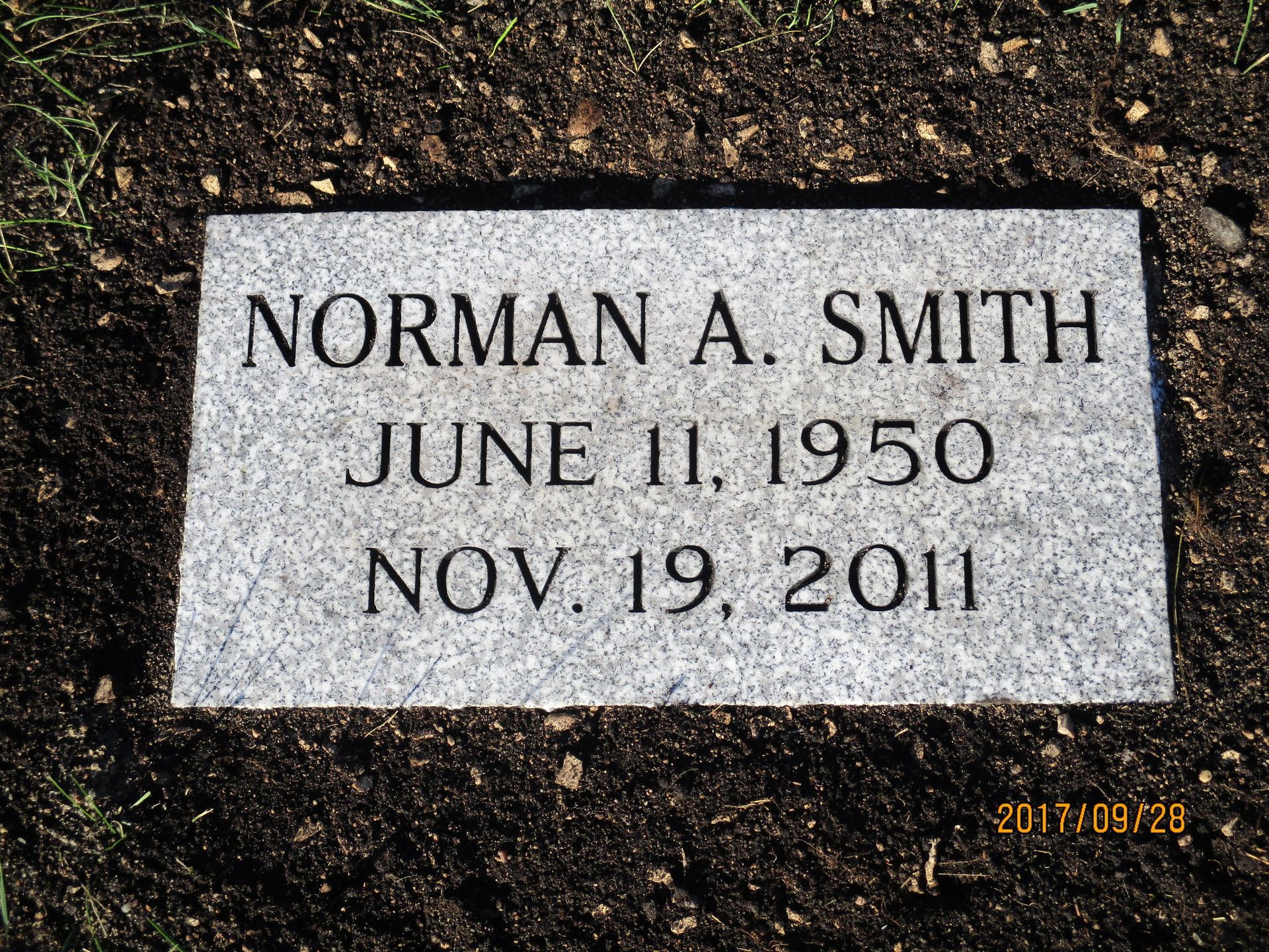 Gravestone for Norman A. Smith with birth and death dates, set in soil outdoors