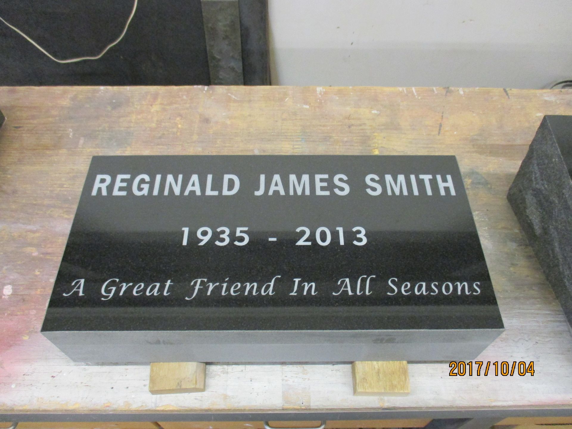 Black memorial plaque for Reginald James Smith, 1935–2013, reading “A Great Friend In All Seasons”