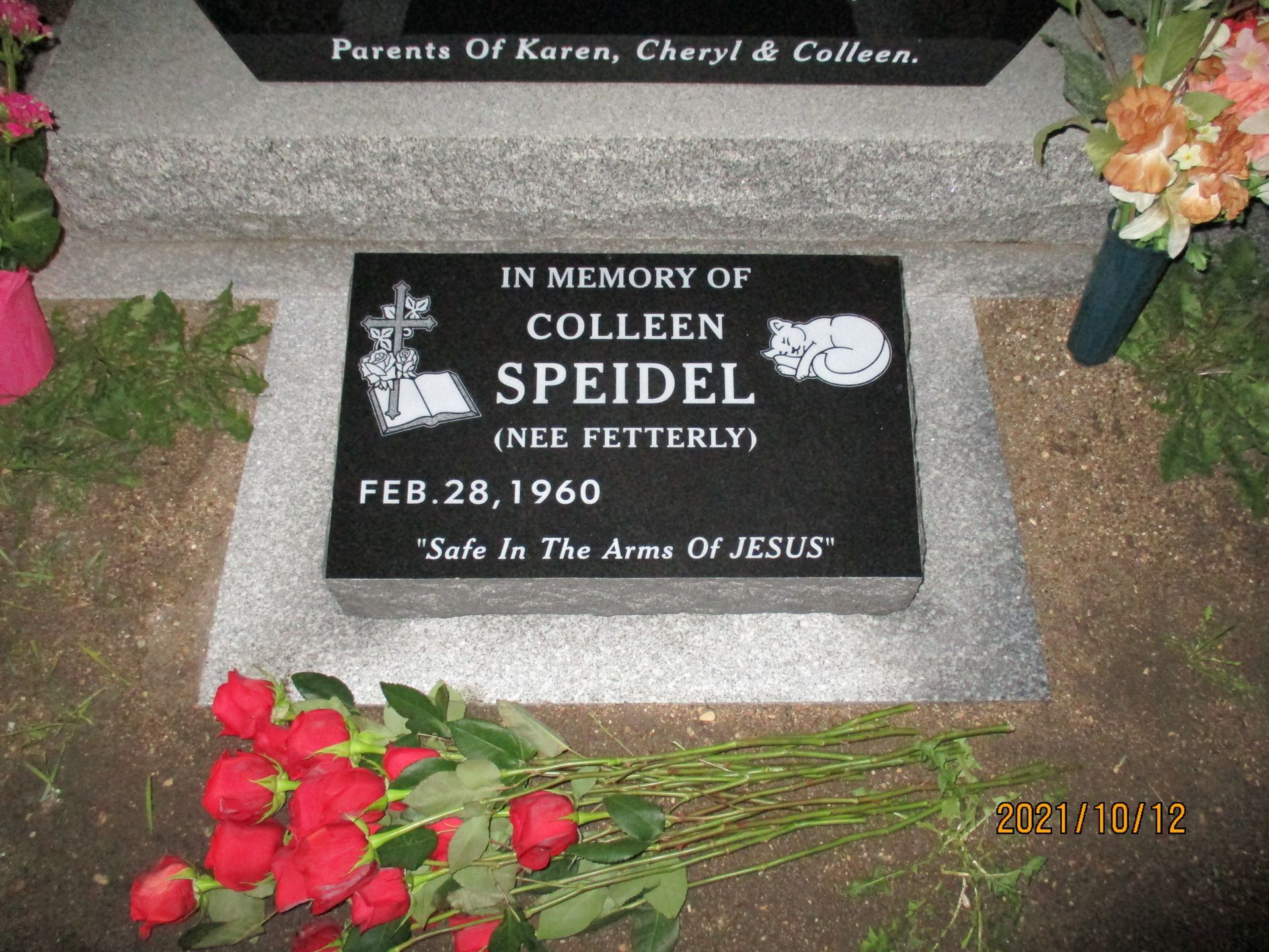 Gravestone plaque for Colleen Speidel with flowers placed around it.