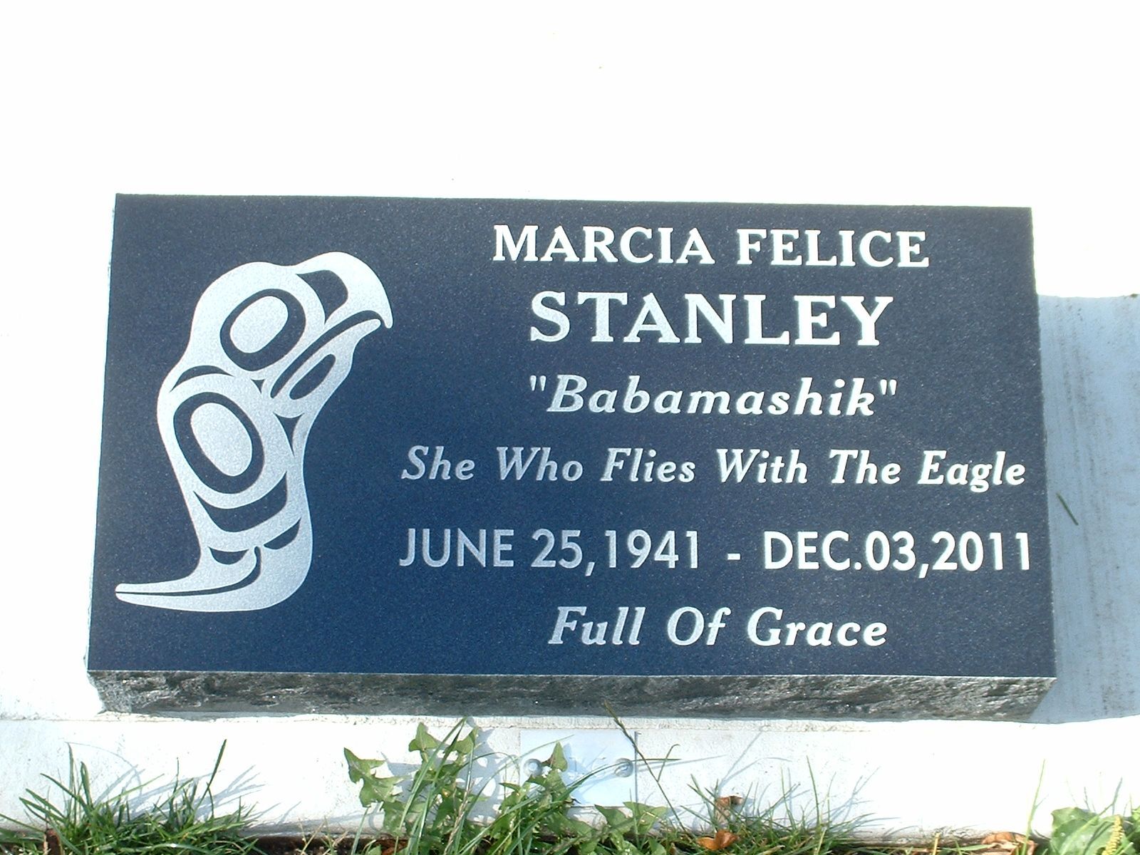 Marcia Felice Stanley memorial plaque with eagle carving and dates, reading “She Who Flies With The Eagle.”