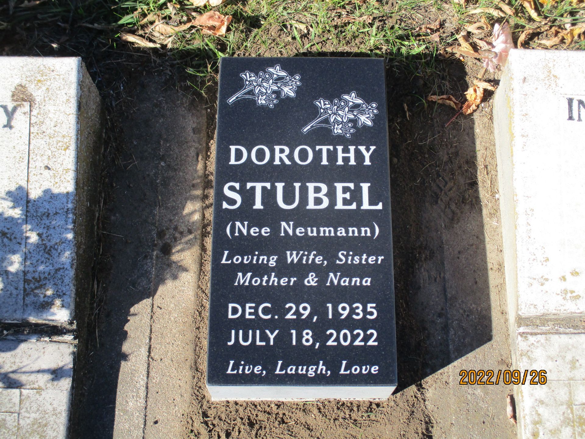 Black grave marker for Dorothy Stubel with white text and flowers, in a cemetery