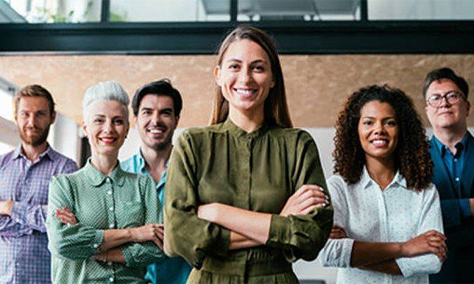 Group of diverse people with arms crossed, smiling confidently in an office setting.