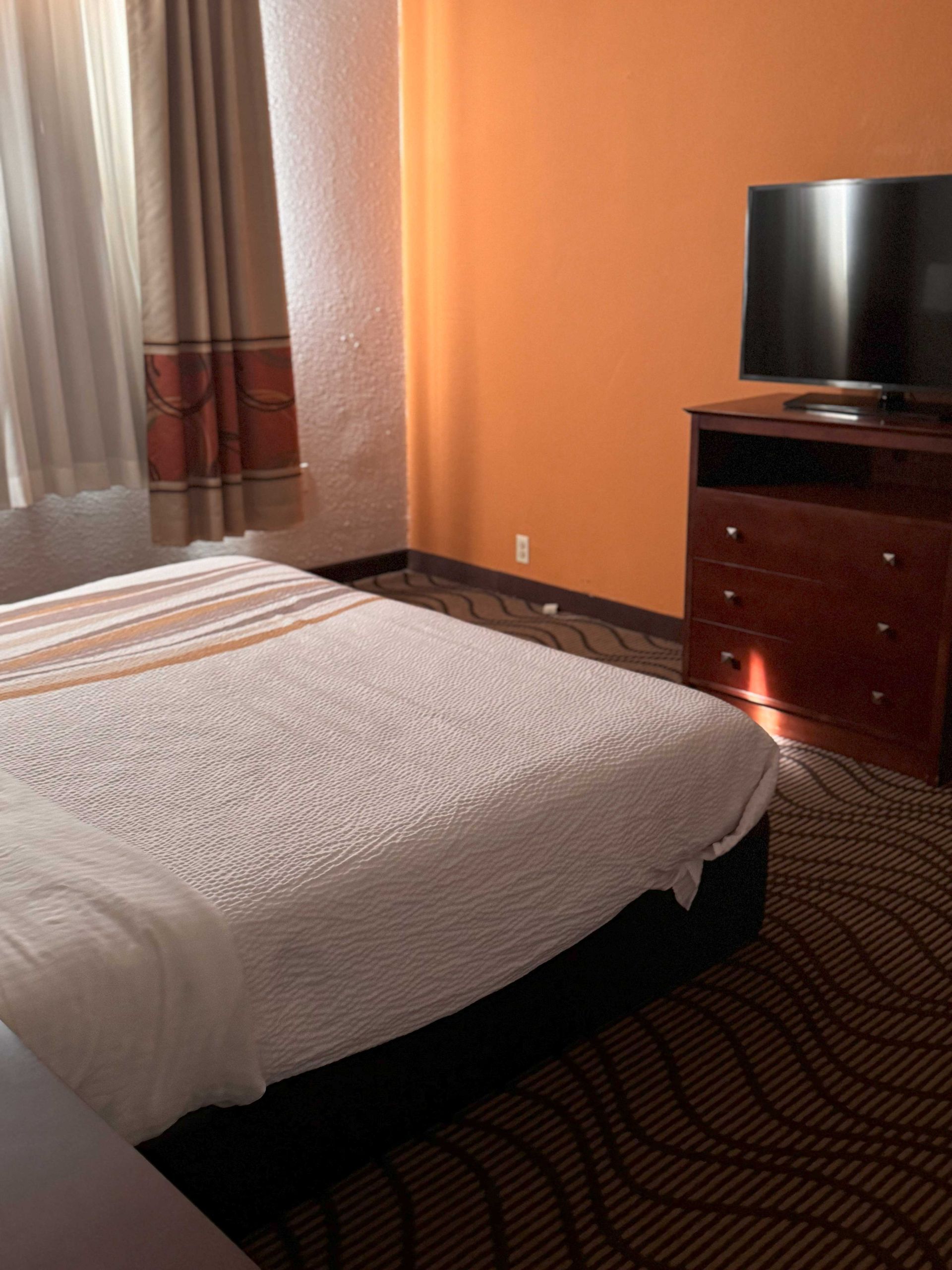 A hotel room with a king size bed and a flat screen tv.