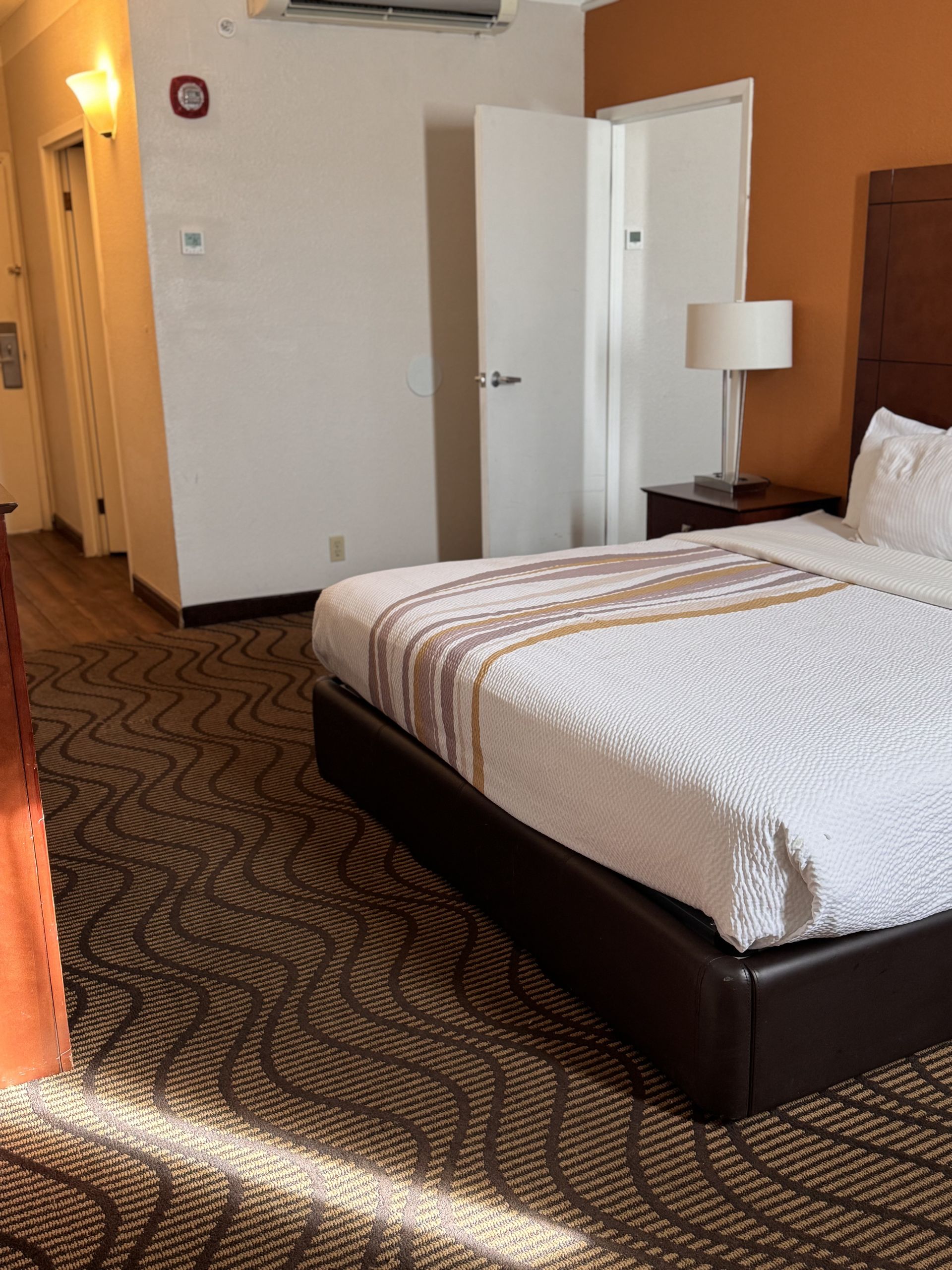A hotel room with a king size bed and a lamp