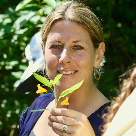 A woman is holding a flower in her hand and smiling
