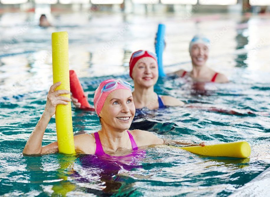 Two women are sitting in a swimming pool talking to each other.