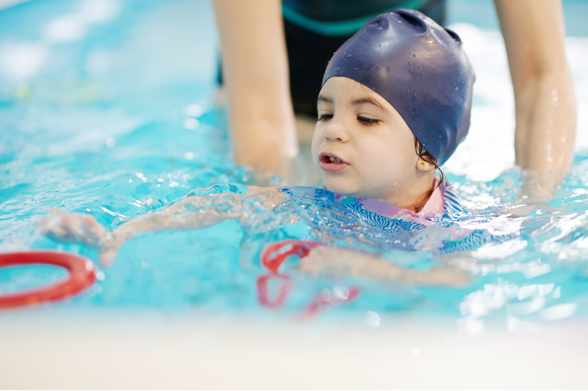 A woman is teaching a child how to swim in a swimming pool.