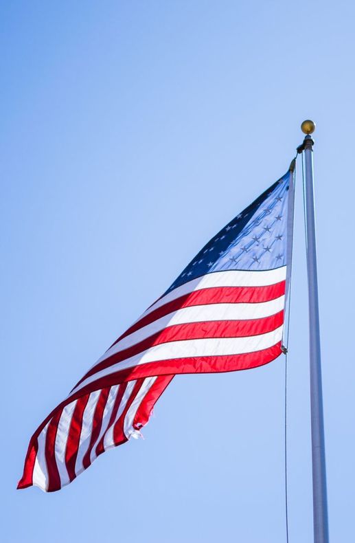 American flag waving on a flagpole against a clear blue sky