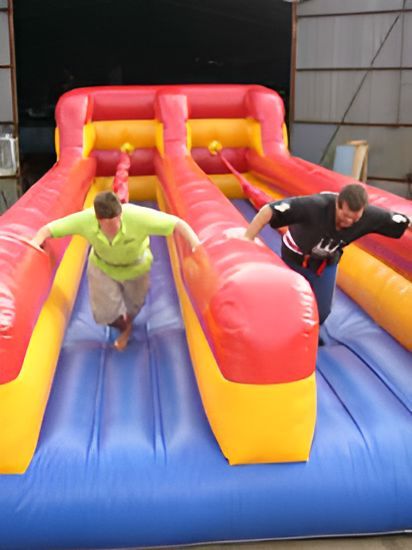 Two Men Racing on a Red, Yellow, and Blue Inflatable Slide — Fun Time Amusements in Gracemere, QLD
