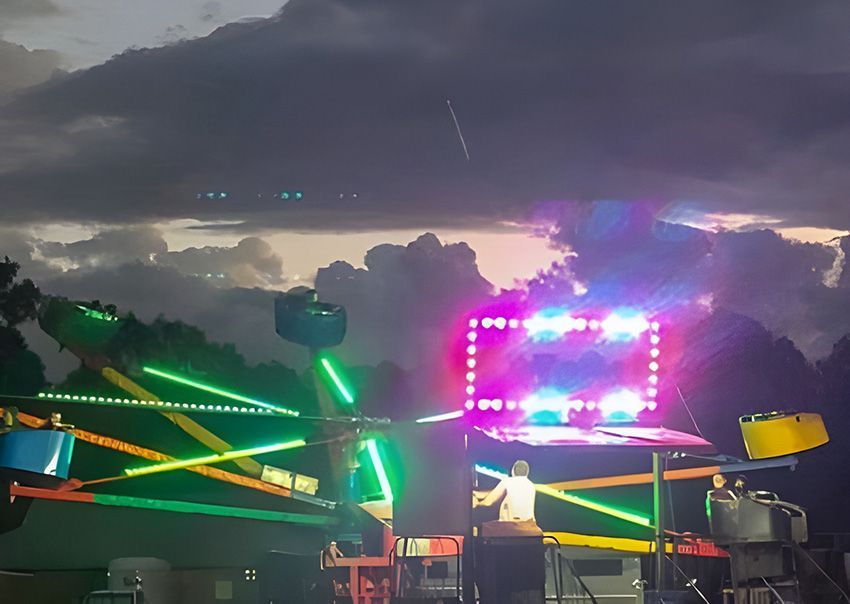 A Carnival Ride is Lit Up at Night With a Cloudy Sky in the Background — Fun Time Amusements in Gracemere, QLD