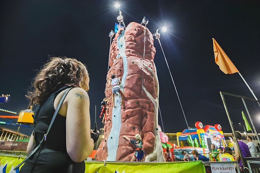 A Woman is Standing in Front of a Climbing Wall at a Carnival — Fun Time Amusements in Gracemere, QLD