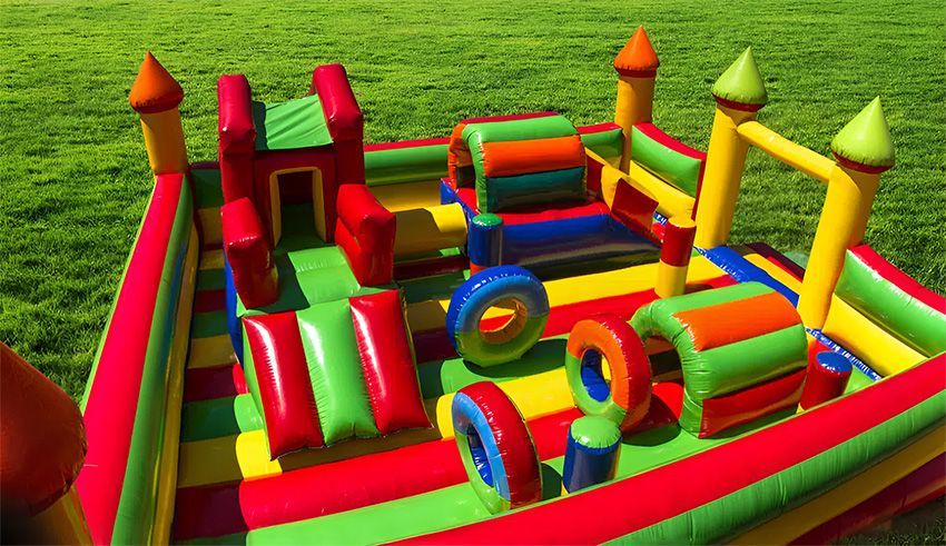 A Large Colourful Bouncy House on Top of a Lush Green Field — Fun Time Amusements in Emerald, QLD