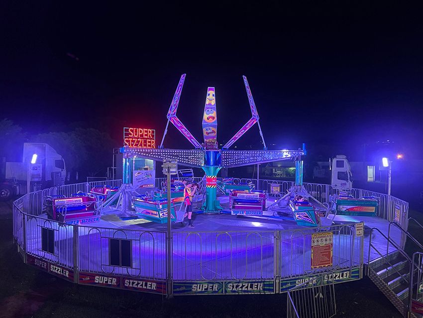 A Carnival Ride is Lit Up at Night With Purple Lights — Fun Time Amusements in Emerald, QLD