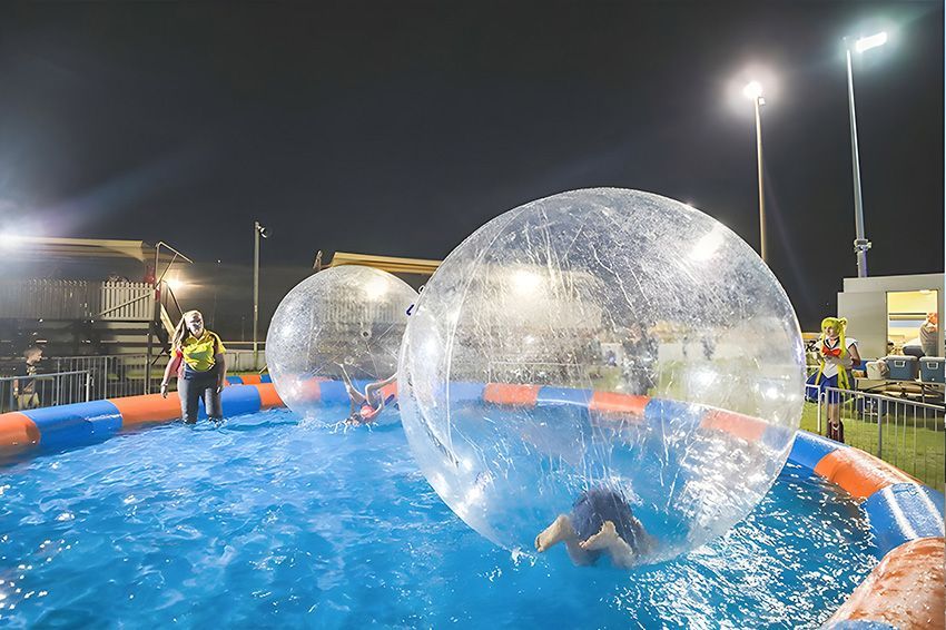 A Group of People Are Playing With Water Bubbles in a Pool at Night — Fun Time Amusements in Gracemere, QLD
