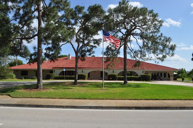Building with red tile roof, arched entryways, and American flag.