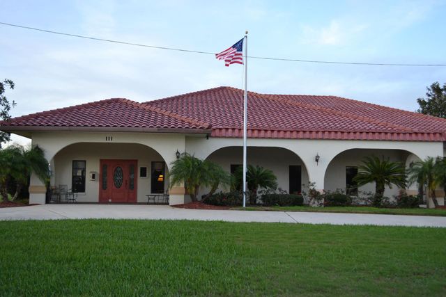 Building with red tile roof, arched entryways, and American flag.