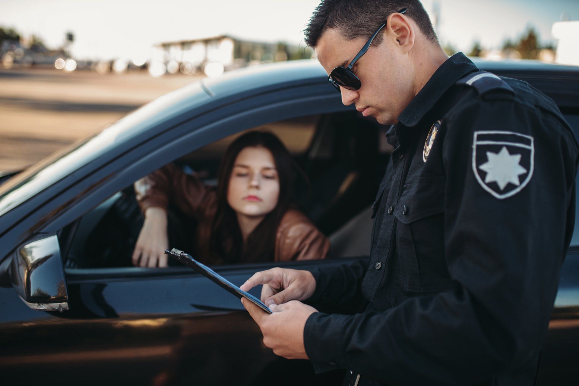 Police officer speaking with driver through car window at roadside check