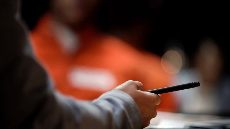 Hand holding a pen over a desk