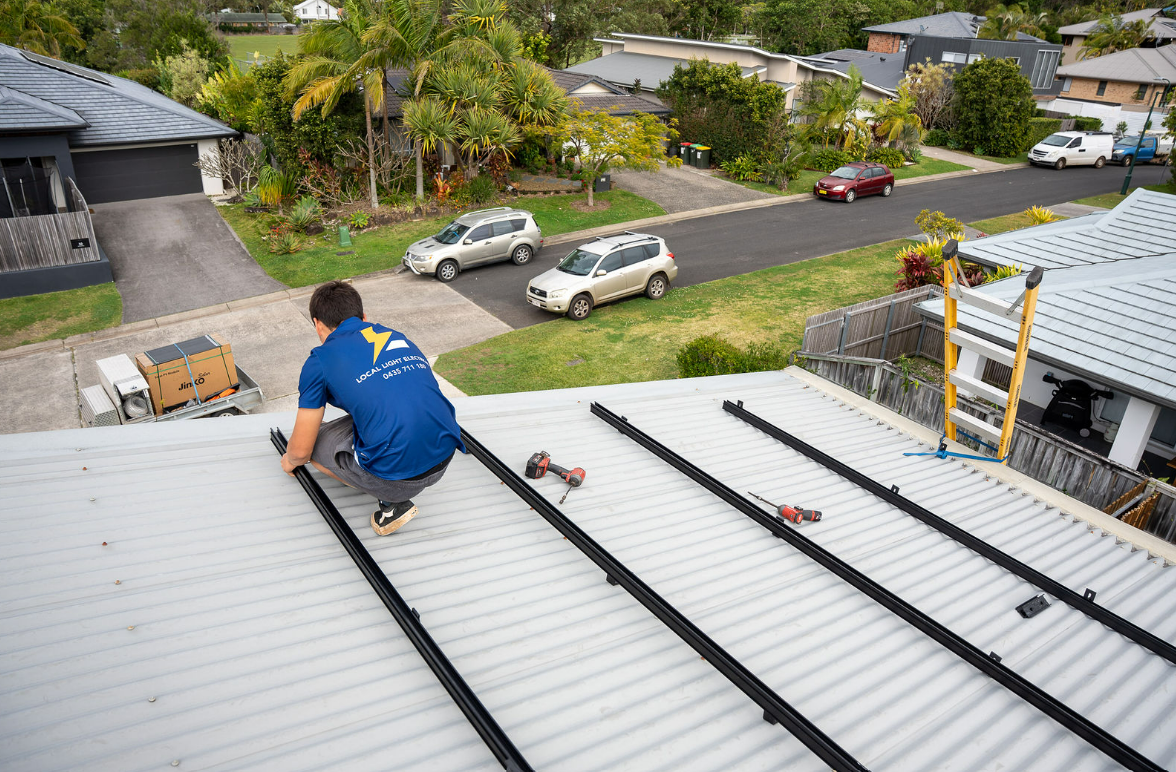 Worker in Blue Shirt Installing Metal Roofing Panels on a White Roof — Local Light Electrical in Suffolk Park, NSW