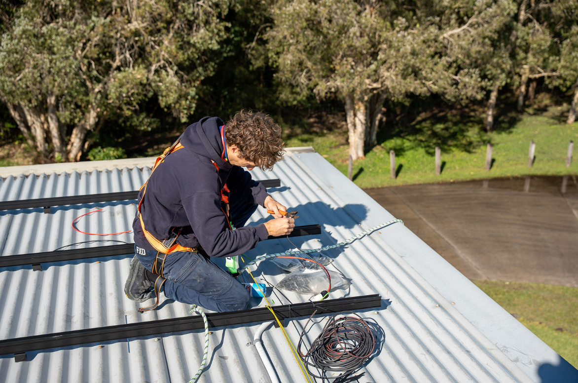 Workers on a Metal Roof Installing Wiring or Equipment Outdoors — Local Light Electrical in Mullumbimby, NSW