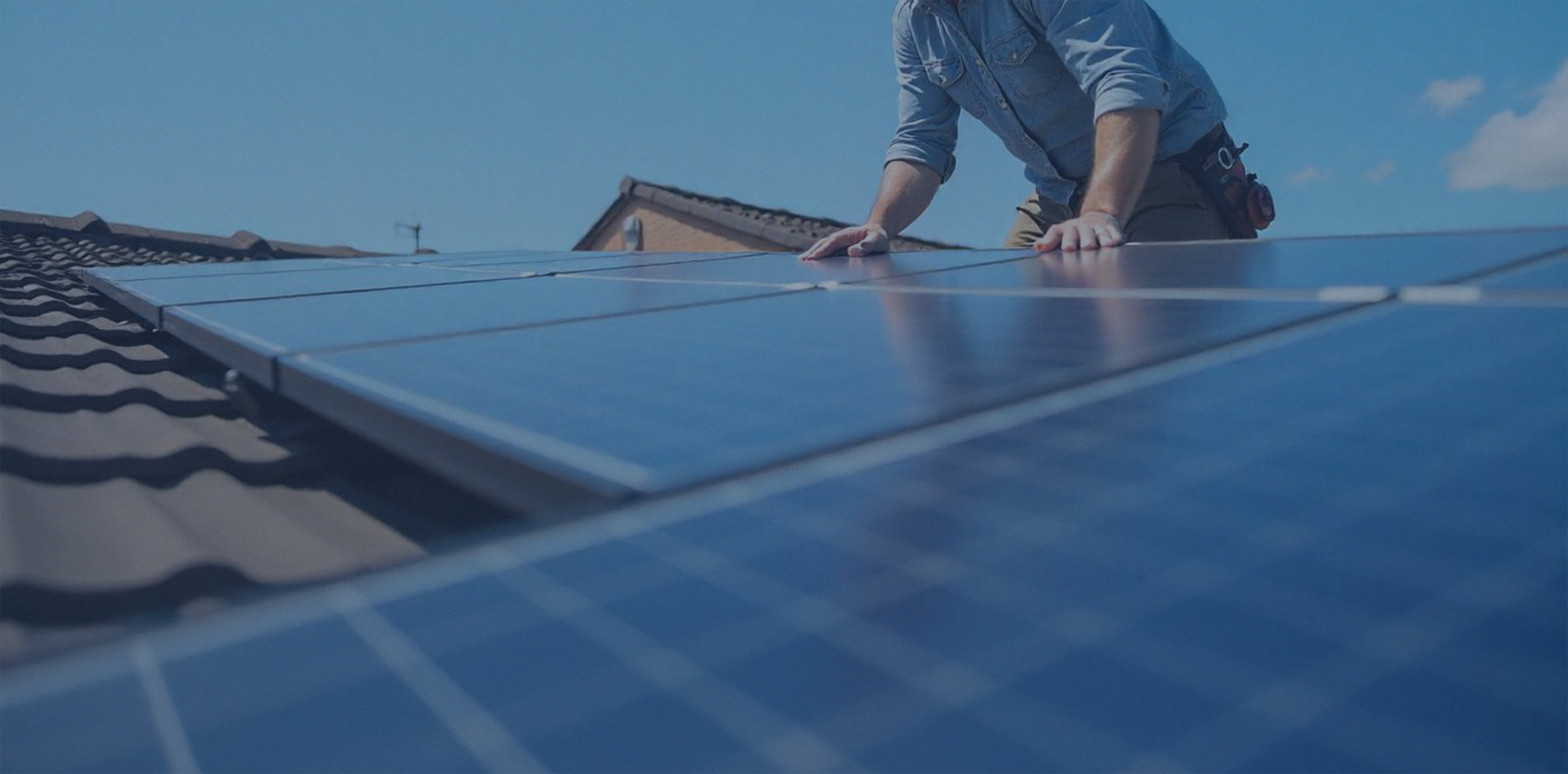 Worker Installing Solar Panels on A Rooftop, with Blue Panels Covering the Roof — Local Light Electrical in Suffolk Park, NSW