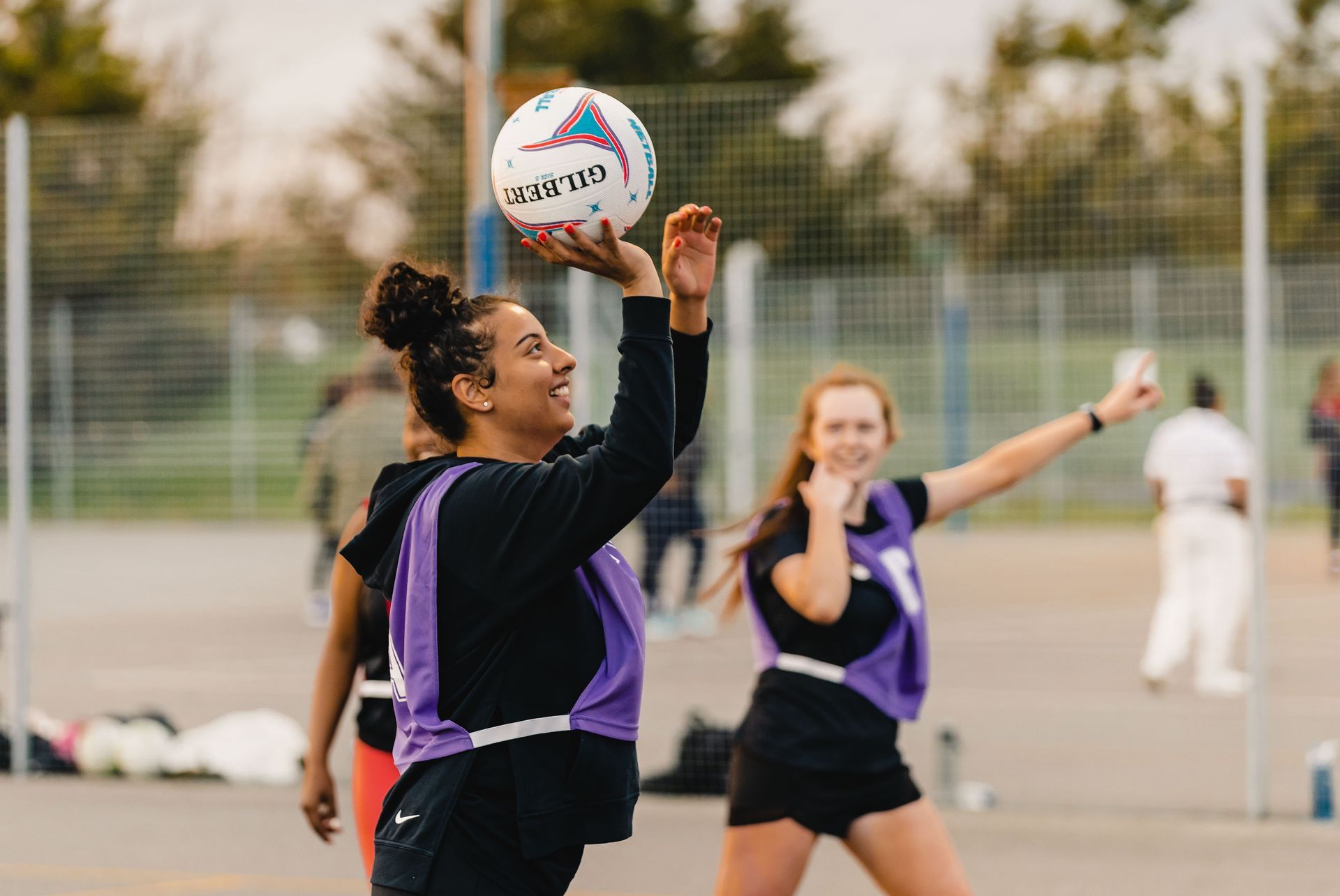 A group of young women are playing netball on a court.
