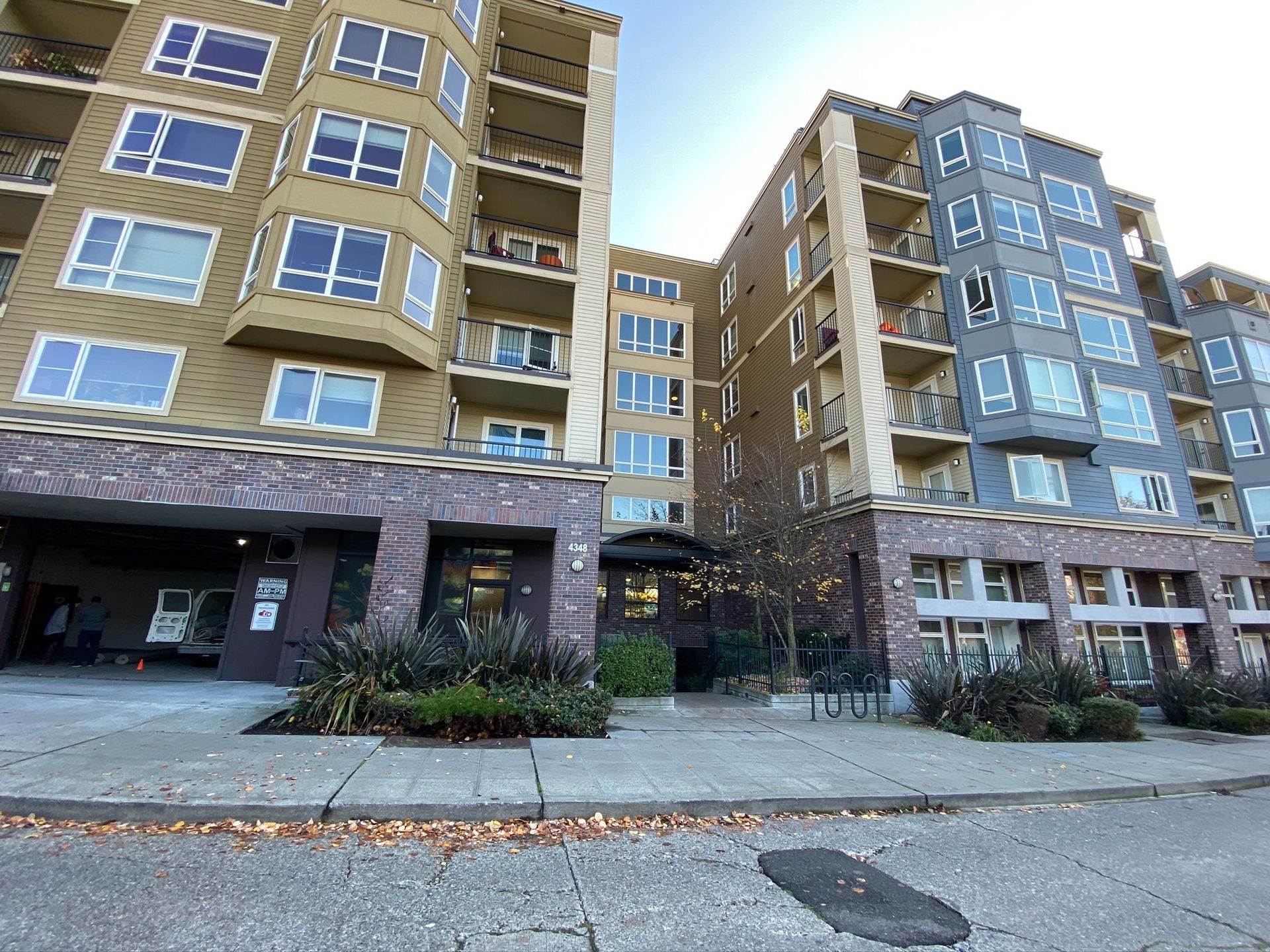 Two modern apartment towers with brick ground floors and blue-tinted windows along a street.