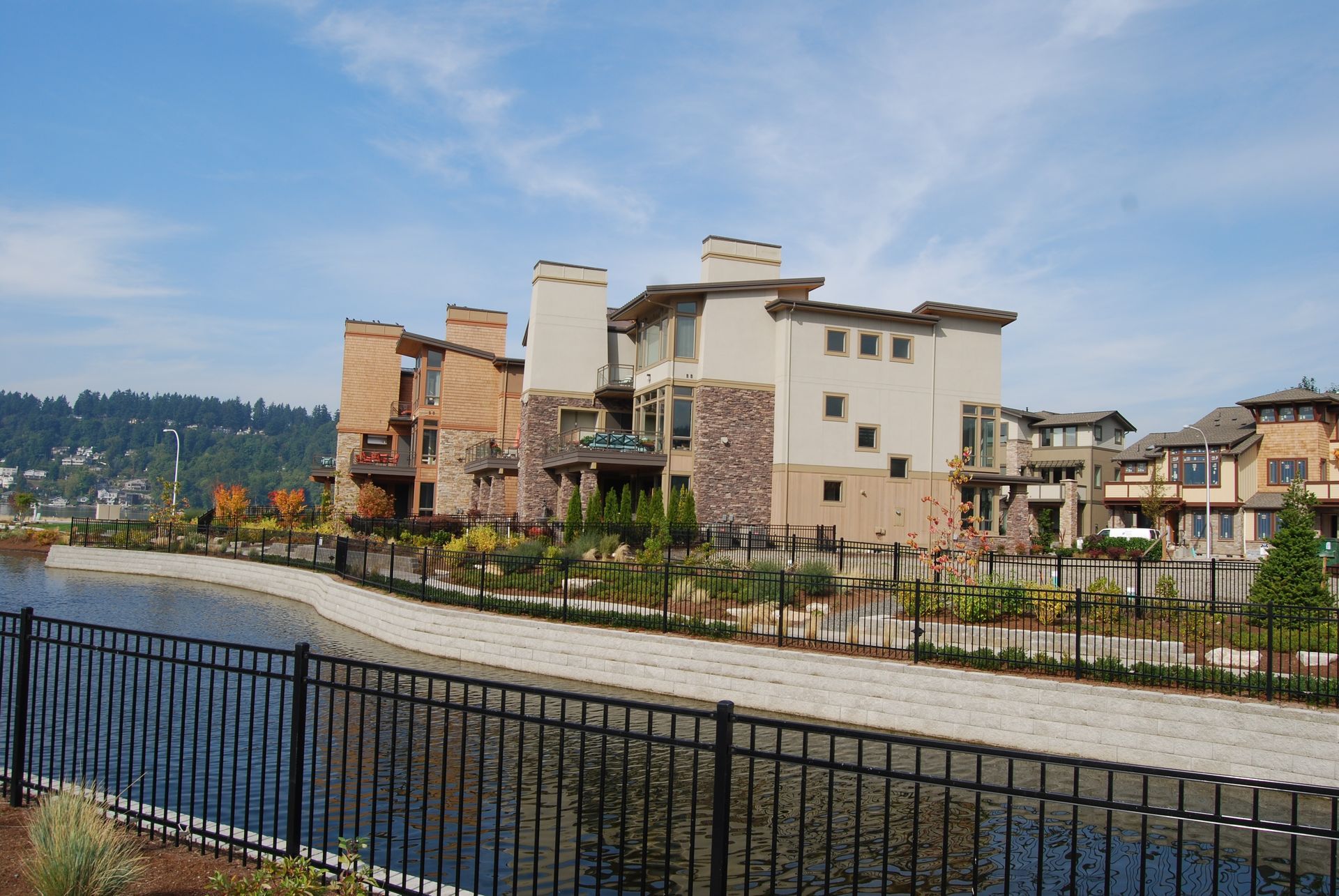 Riverside promenade with modern apartment buildings and a black metal fence under a cloudy sky