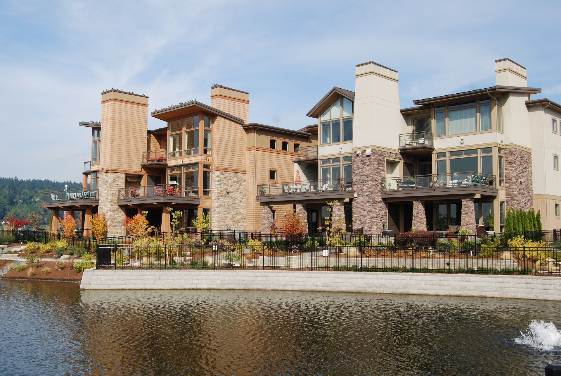 Waterfront stone-and-stucco resort buildings with chimneys and balconies beside a calm river.