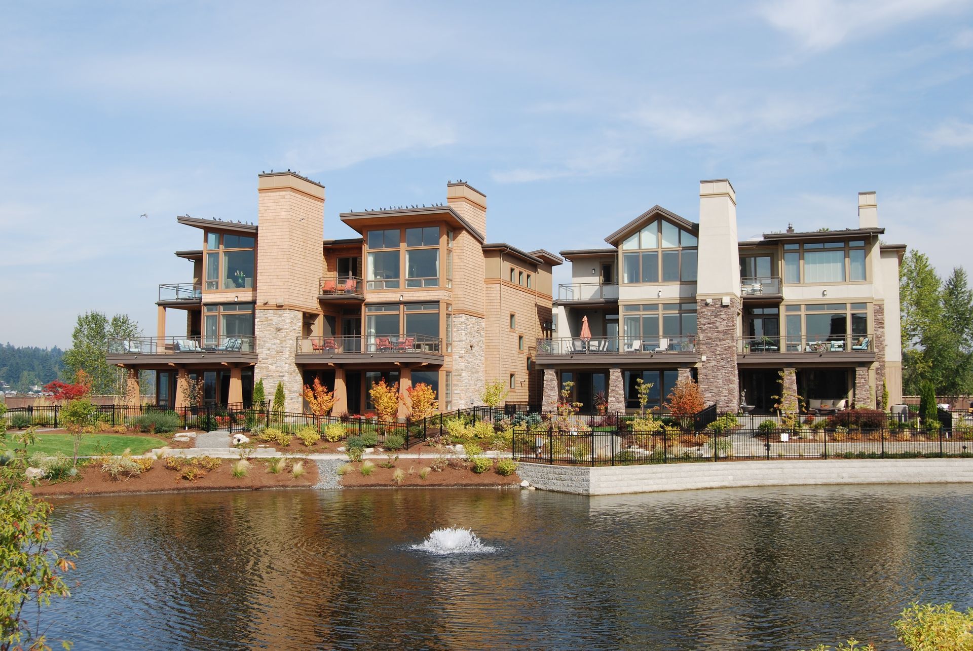 Modern lakeside townhouses with stone and wood facades reflected in calm water