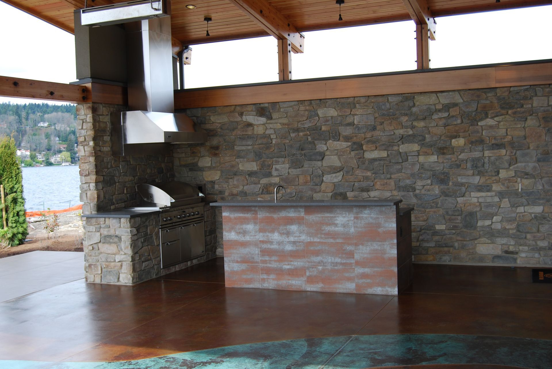 Stone patio with covered outdoor bar and lake view in the background