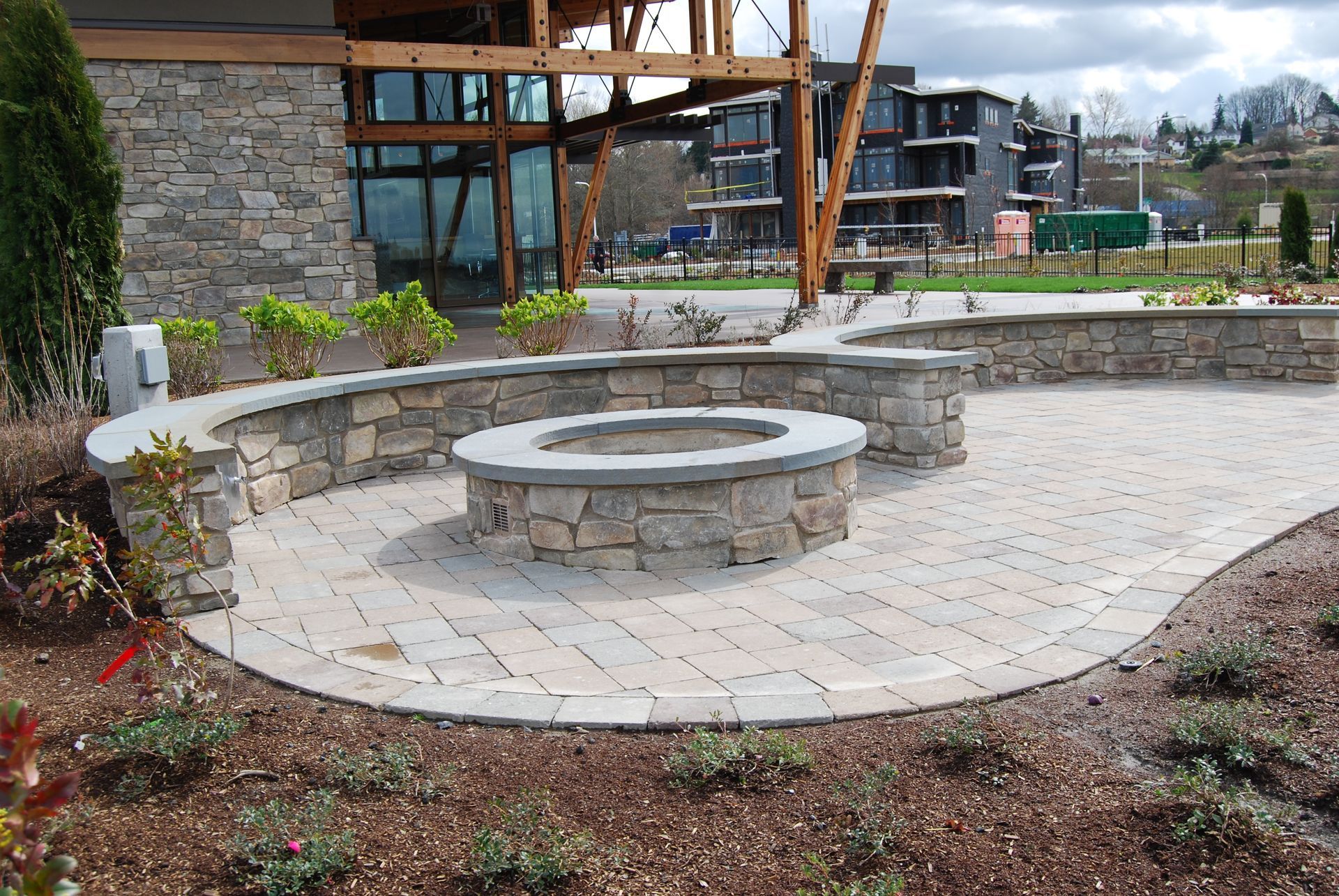 Stone patio with circular seating, low curved wall, and modern building in the background