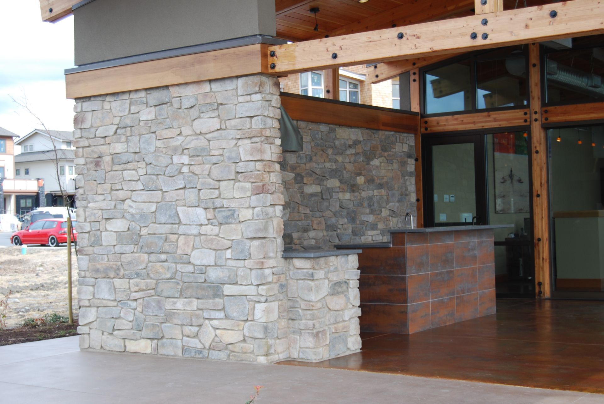 Stone-and-wood building entrance with covered walkway and glass doors