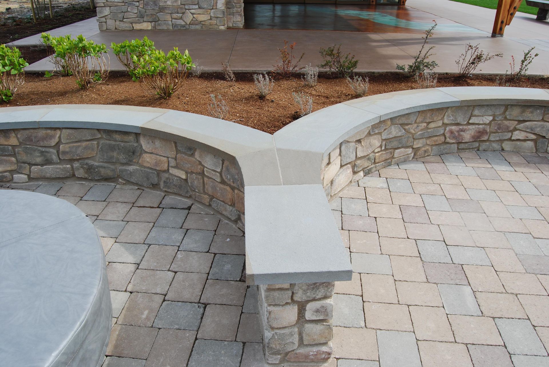 Stone curved seating around a paved patio with a central planter