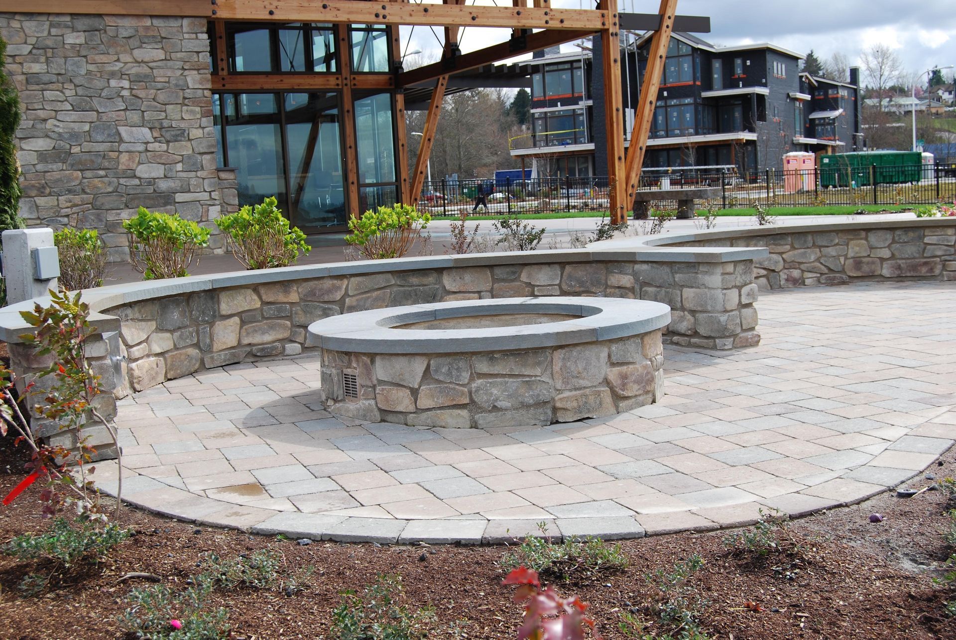Stone circular seating area in a landscaped courtyard with a stone building and modern windows behind it