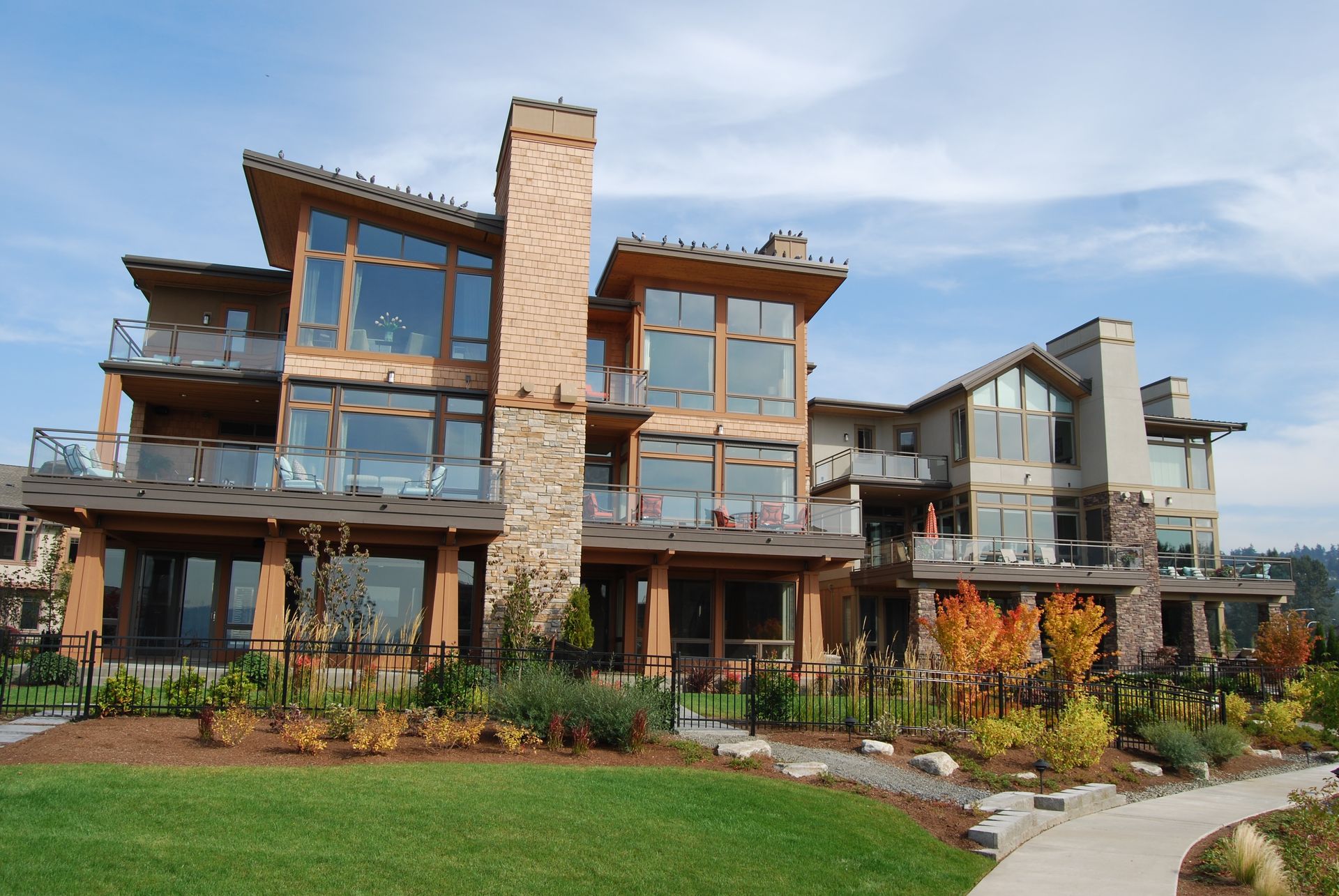 Modern multi-story apartment building with glass balconies and landscaped lawn under a blue sky