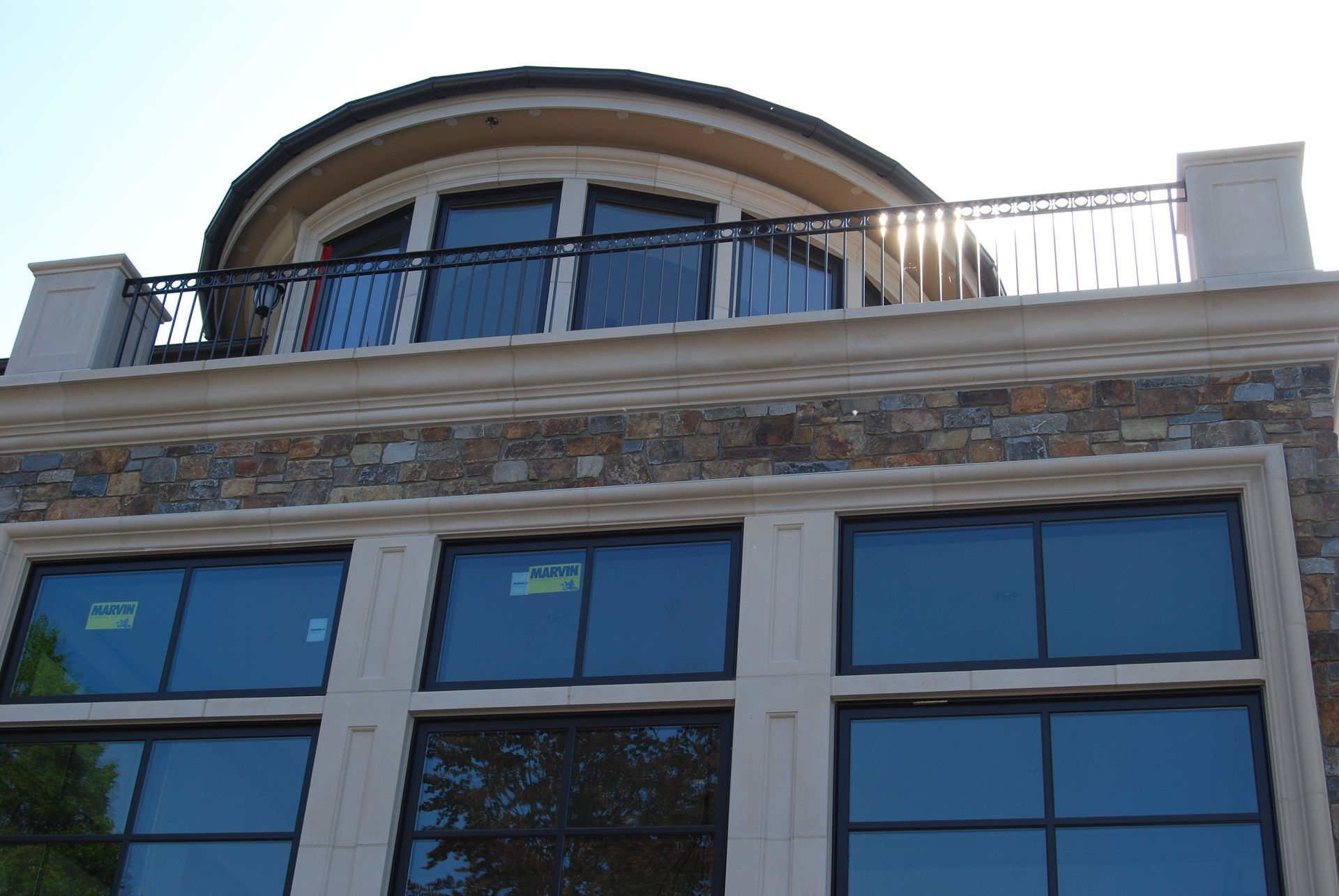 Modern building facade with blue-tinted windows and a curved balcony on the rooftop