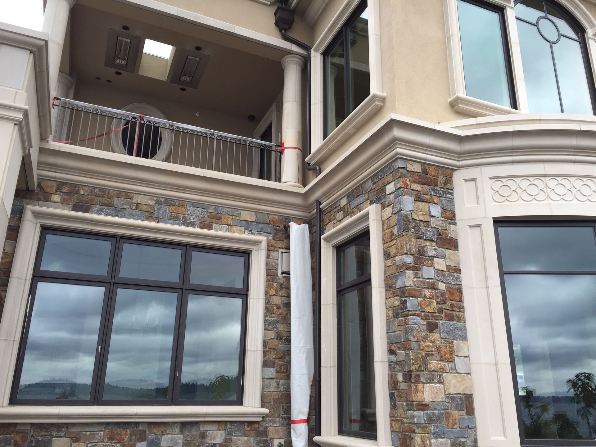 Modern multi-story house exterior with stone facade, large windows, and a balcony