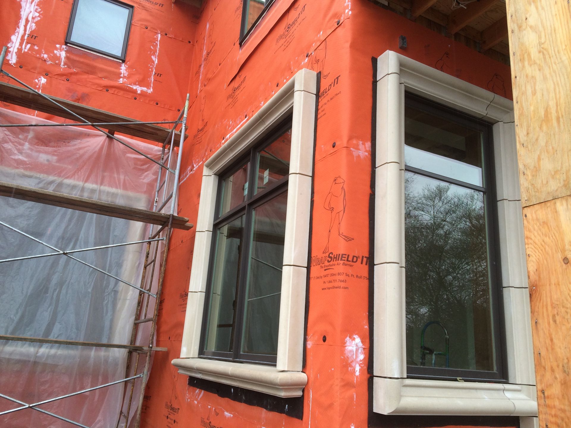 Orange building wall with two white-framed windows and a reflective glass door or panel