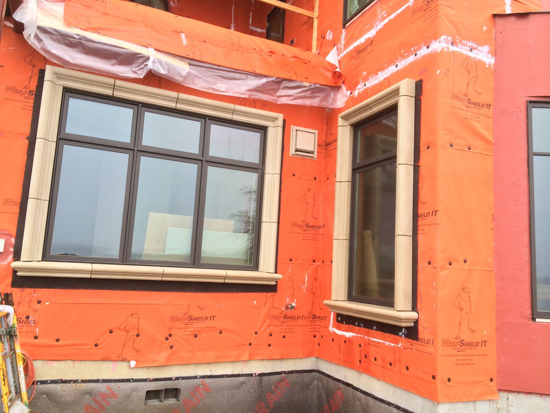 Orange building exterior with two windows and a narrow doorway beneath a gray roofline