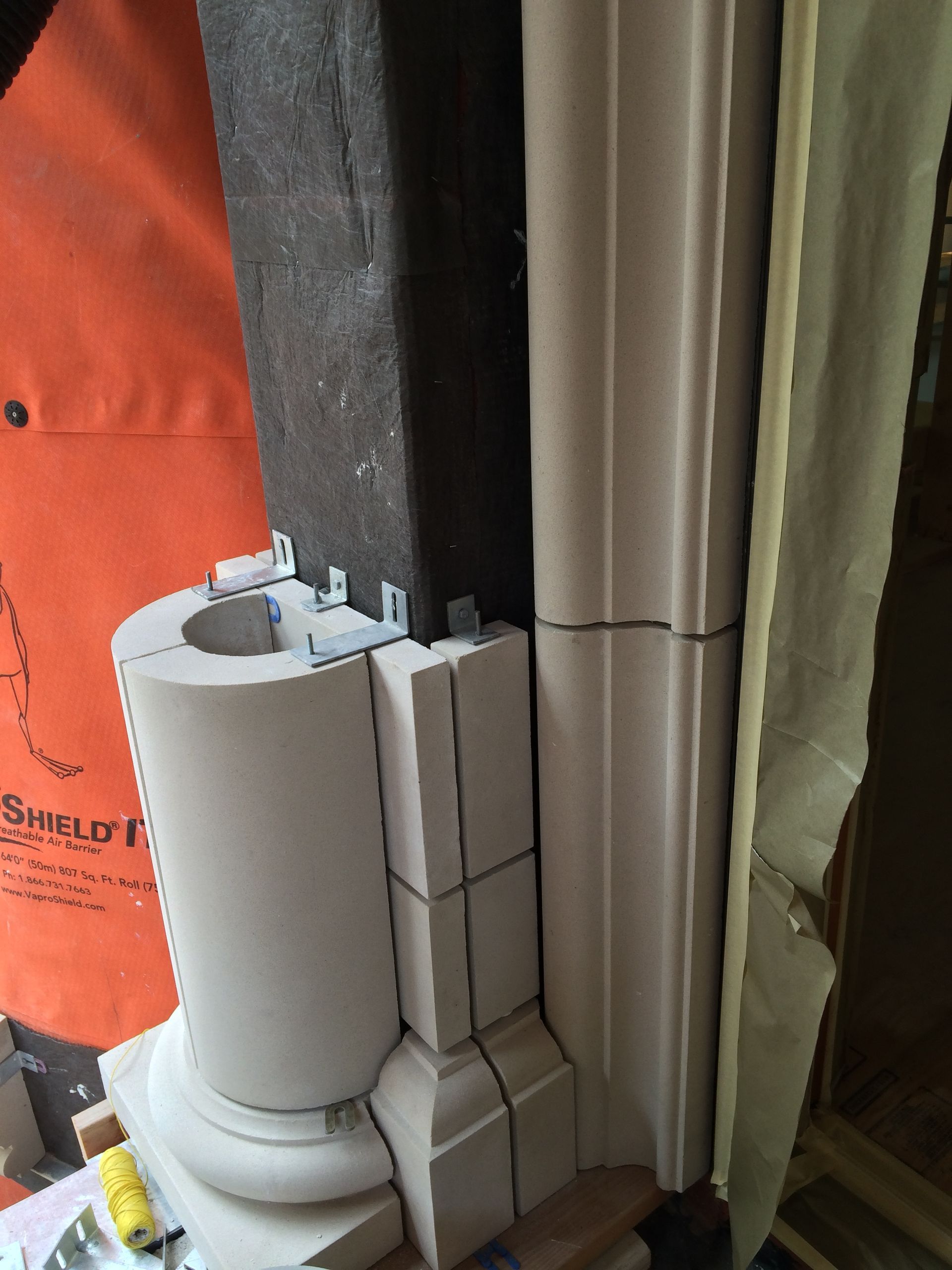 White paper towel roll on a holder beside a window with stacked white boxes and curtains